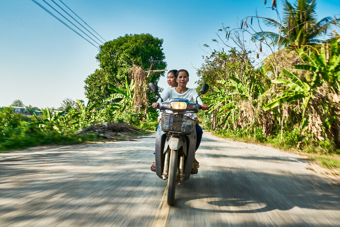 Two people riding a motorcycle down a rural road surrounded by greenery, highlighting water's powerful impact.