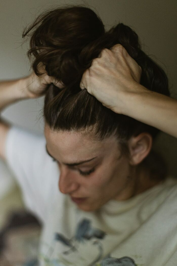 Person with distressed expression pulling hair back, representing intense moments in psych wards nursing stories.