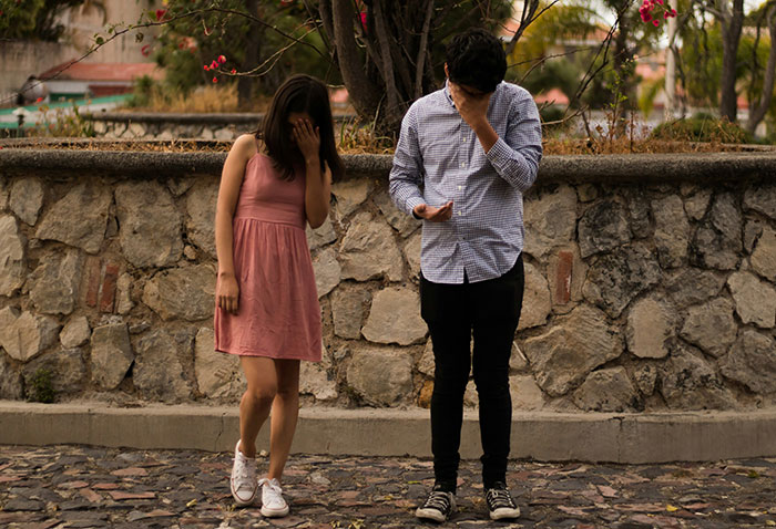 Young couple with upset expressions standing apart outdoors, depicting a toxic relationship and emotional conflict.