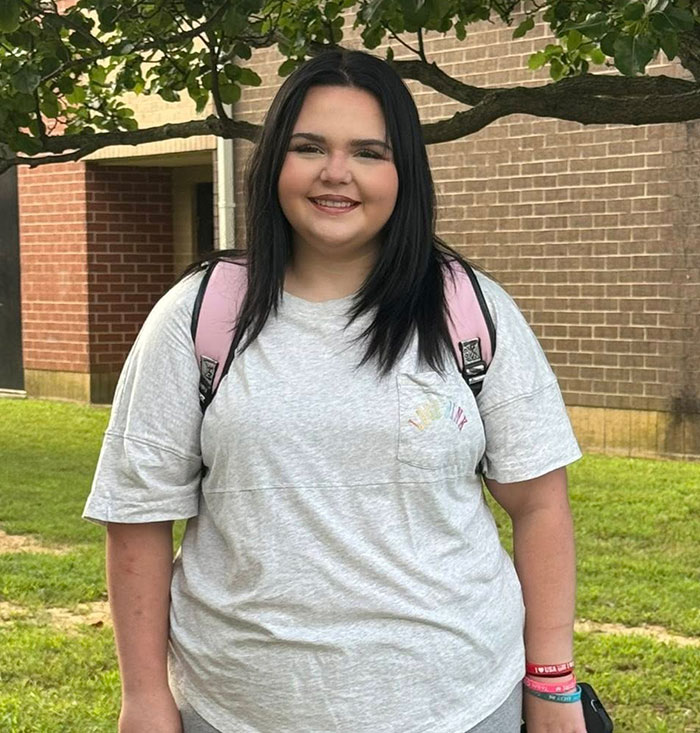 Teen girl with backpack smiling outdoors, facing relentless bullying at school over racist name before changing it.