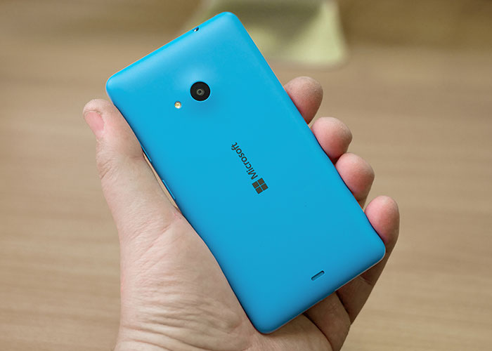 Hand holding a blue Microsoft phone, representing companies competing for the corporate Darwin award for business failures.