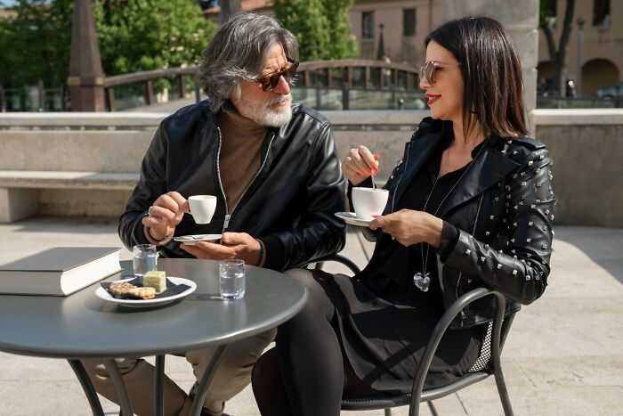 Older man and younger woman enjoying coffee together outdoors, sharing moments related to dating older people stories single.