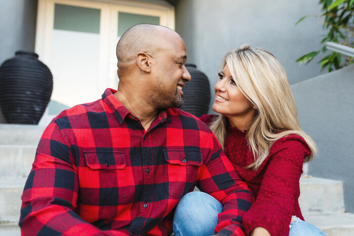 Couple smiling and sitting close together outdoors, illustrating dating older people stories in a single moment.