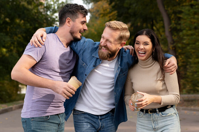 Three friends sharing laughs outdoors, enjoying coffee and happy moments related to dating older people stories single.