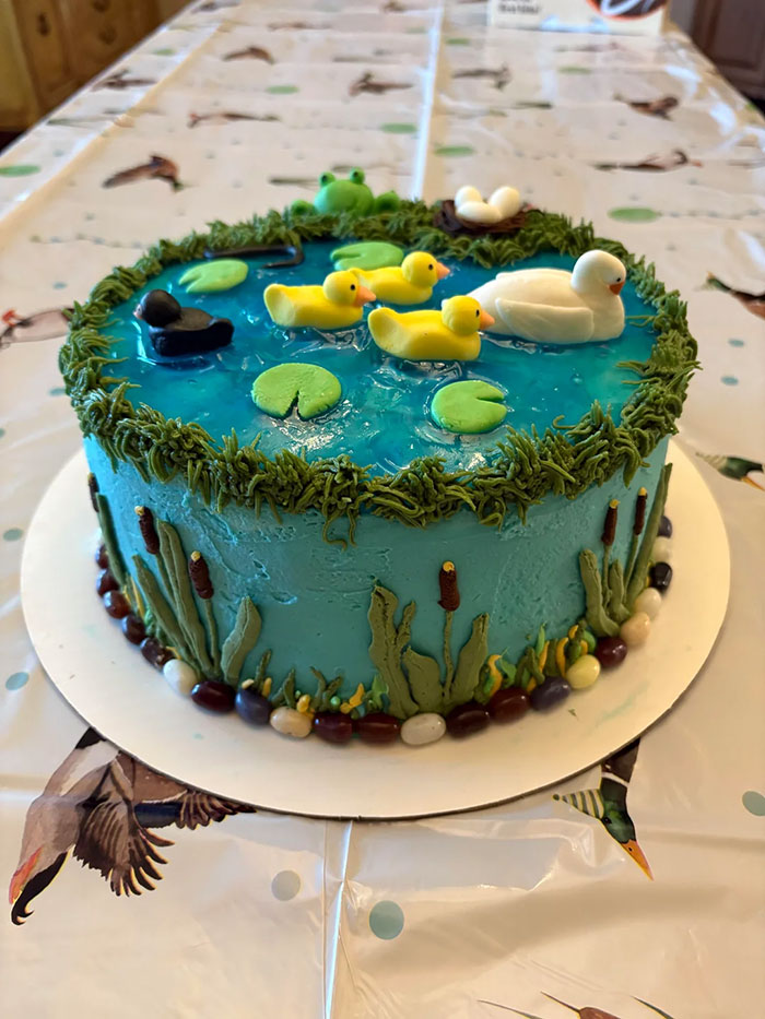 Decorated baked goods cake with pond scene featuring ducks, lily pads, grass, and reeds, showcasing gorgeous baked goods artistry.