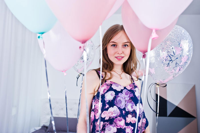Teen girl surrounded by pink and blue balloons, reflecting 13YO refusal to invite one girl from school story.