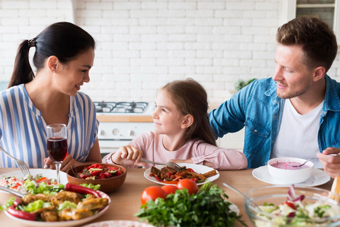 Foodie woman and family sharing a meal at the table, highlighting a foodie woman dealing with buttered noodles. Foodie woman and family sharing a meal at the table, highlighting a foodie woman dealing with buttered noodles.