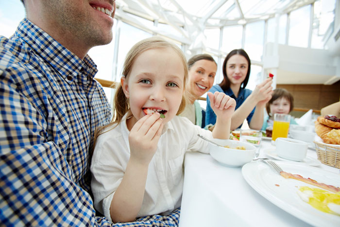Family enjoying a meal together at a bright restaurant, highlighting a foodie woman and a child sharing food moments. Family enjoying a meal together at a bright restaurant, highlighting a foodie woman and a child sharing food moments.
