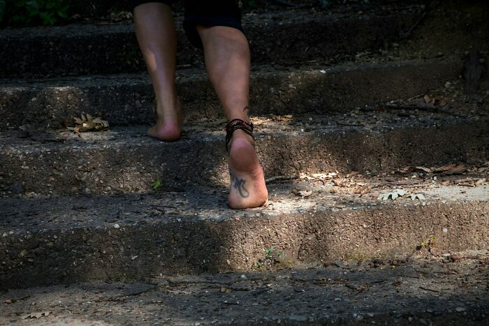 Bare feet walking up outdoor stone steps with ankle bracelets, illustrating culture shocks experienced while visiting Australia.