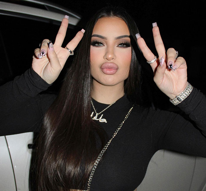 Young singer Delarosa posing with peace signs at night, wearing black top and long straight hair. Young singer Delarosa posing with peace signs at night, wearing black top and long straight hair.
