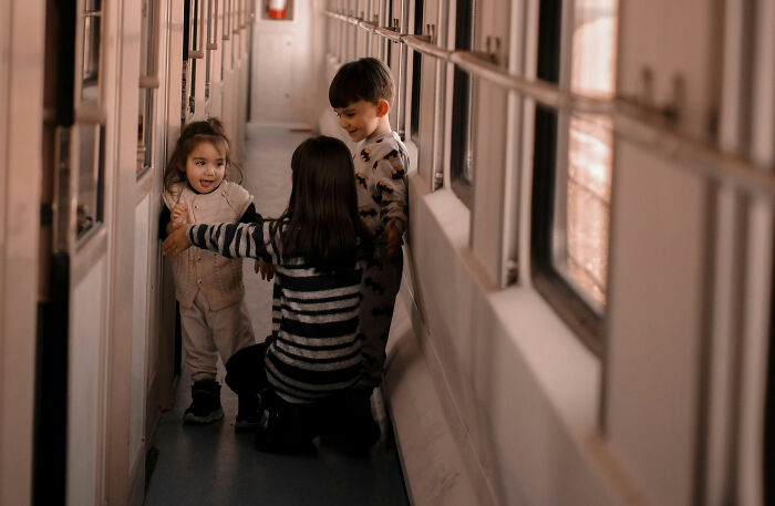 Three young children playing together in a narrow hallway, highlighting grandkids bonding and family moments.