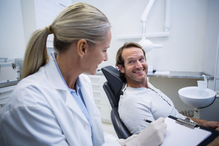 Doctor consulting smiling male patient in a clinical setting, illustrating the concept of Dr Google versus real doctor advice.