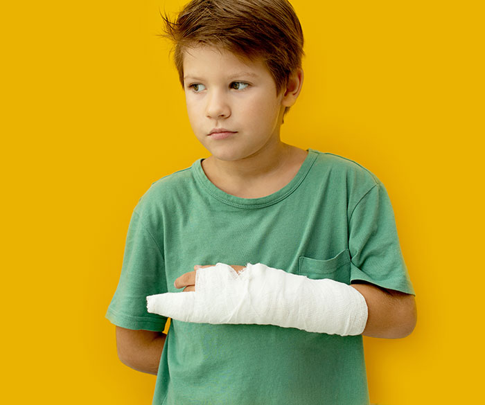 Young boy with a broken arm in a white cast wearing a green shirt, symbolizing surgeons and doctors mistakes in treatment.