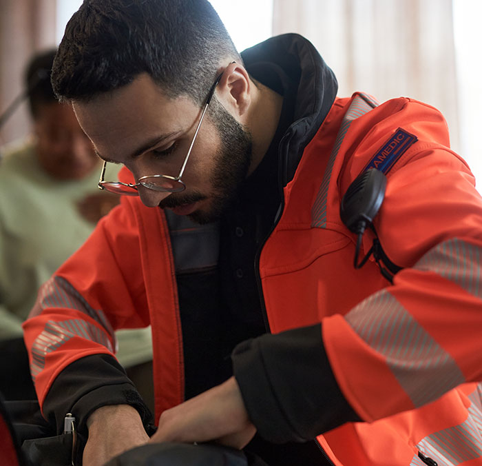 Paramedic in an orange jacket focusing on medical equipment, highlighting experiences shared by surgeons and doctors about mistakes.
