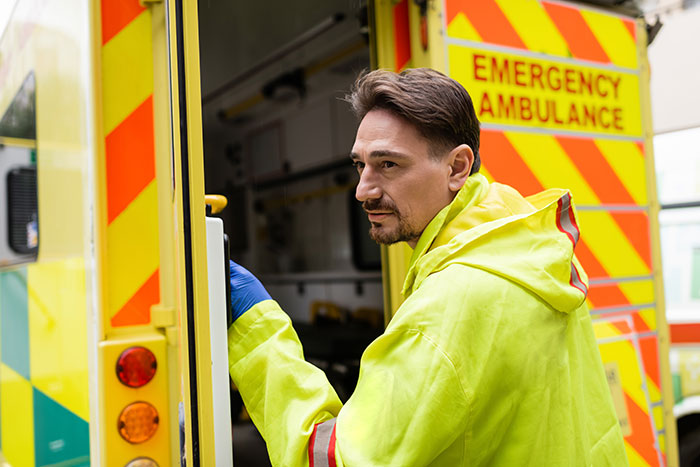 Paramedic in high-visibility jacket entering an emergency ambulance, illustrating doctors and surgeons recalling worst mistakes.