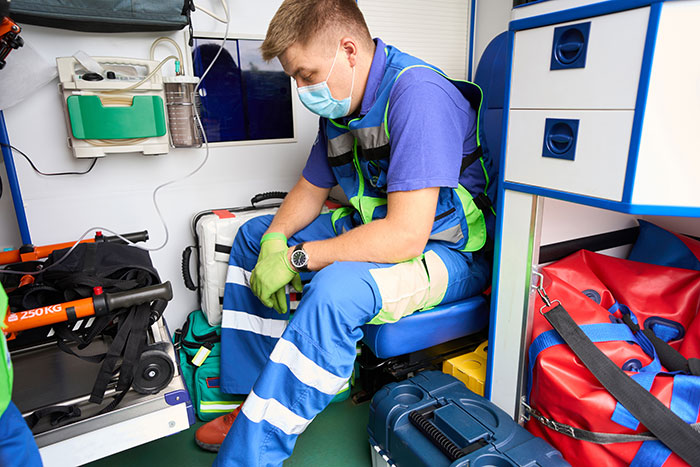 Medical professional wearing a mask and gloves sitting inside an ambulance reflecting on mistakes shared by surgeons and doctors.