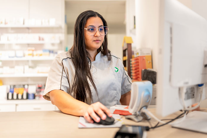 Female doctor wearing glasses and gray scrubs working on a computer in a medical office, reflecting on worst mistakes.