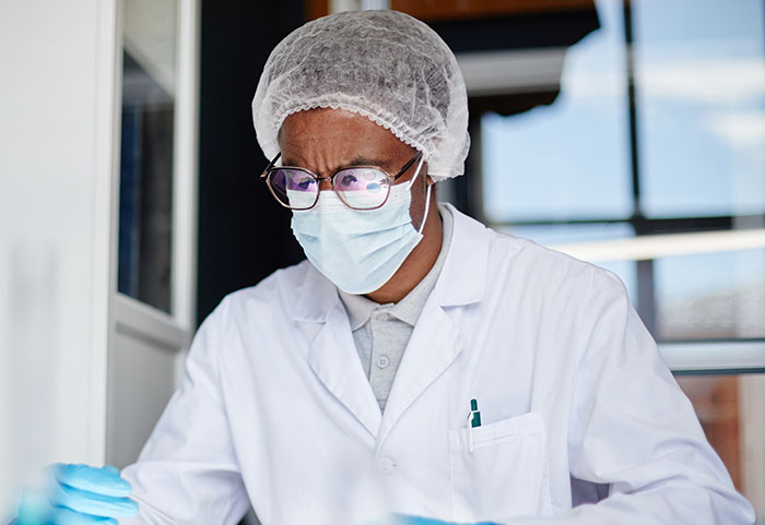 Surgeon wearing glasses, mask, and hairnet focused on work in a bright medical setting recalling difficult moments.