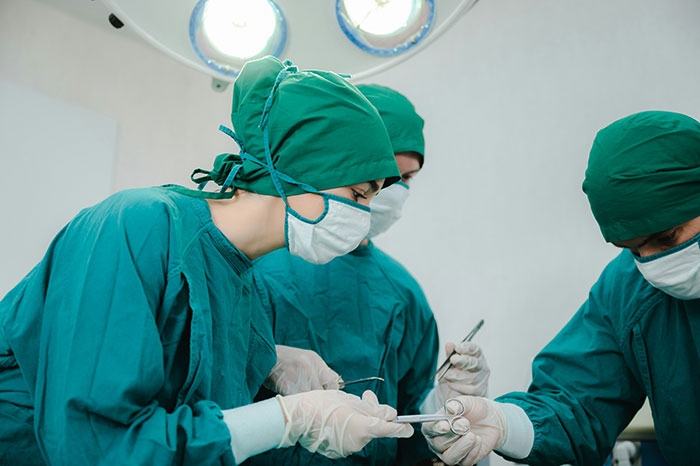 Surgeons in green scrubs and masks performing surgery under bright operating room lights showing doctors messed up moments.