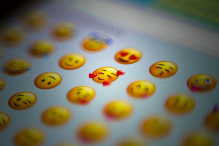 Close-up of colorful emoji icons on a digital screen illustrating the etymology of common words in modern language.