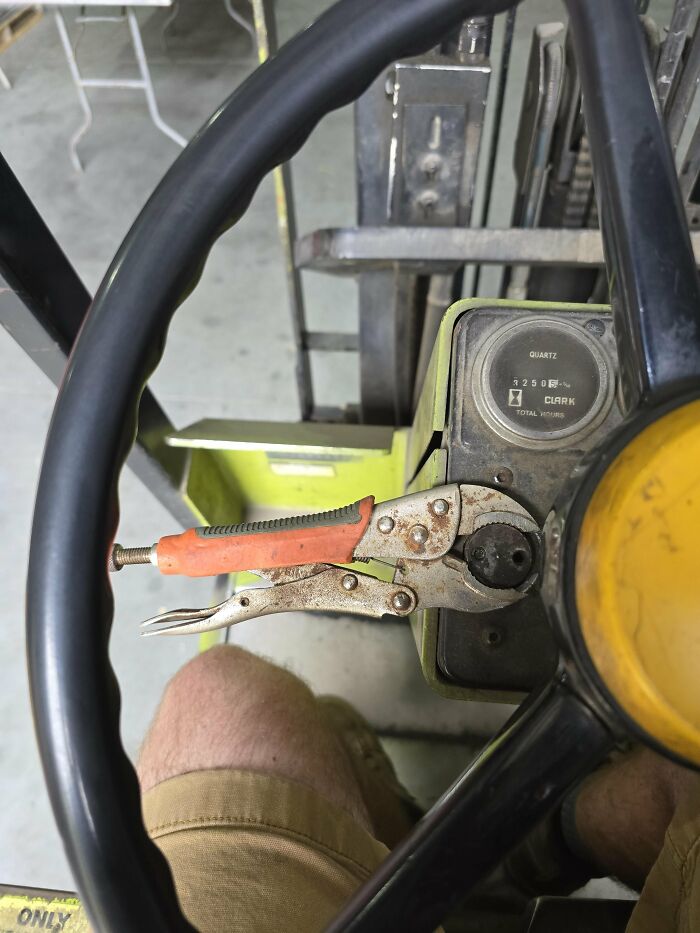 Forklift steering wheel with pliers used as a makeshift adjustment tool, showing a funny example of people not even trying at work.