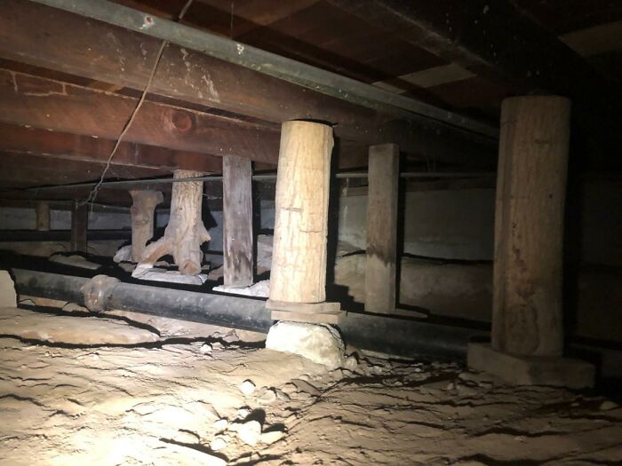 Uneven wooden support posts under a floor showing funny examples of people not even trying in a job.