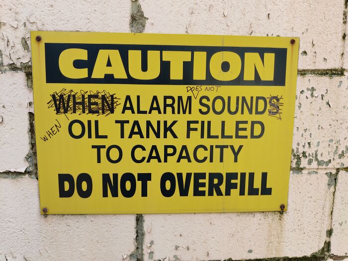 Yellow caution sign on a wall with humorous graffiti showing people not even trying to follow instructions.