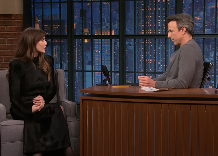 Elizabeth Olsen in a black dress discussing the viral 6,7 meme during a late-night talk show interview.