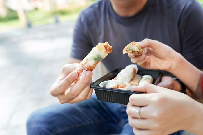 Personas compartiendo rollitos de primavera mientras disfrutan de un momento casual fuera de casa antes de ir al doctor.