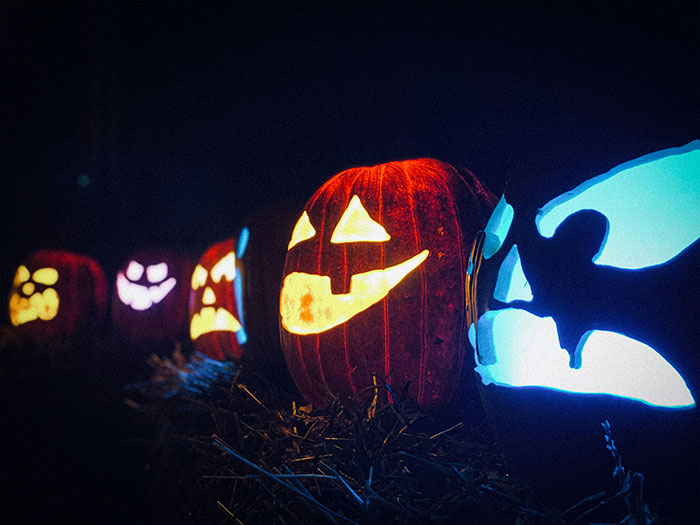 Carved pumpkins glowing at night on a haunted hayride setting with spooky and playful faces.