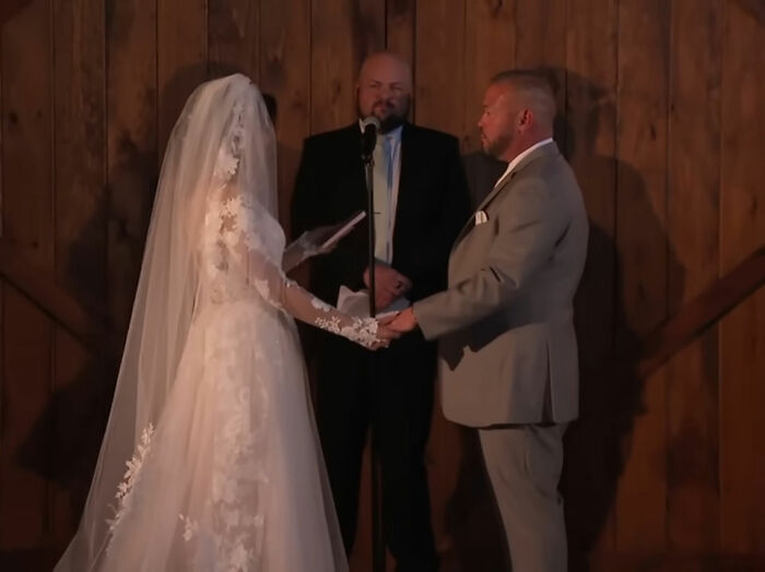 Bride and groom holding hands during an indoor wedding ceremony with officiant in the background, Jon Gosselin remarries. Bride and groom holding hands during an indoor wedding ceremony with officiant in the background, Jon Gosselin remarries.