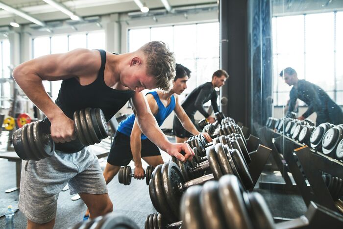 Three men lifting dumbbells in a gym, showcasing strength training while people share favorite true facts that seem unreal.
