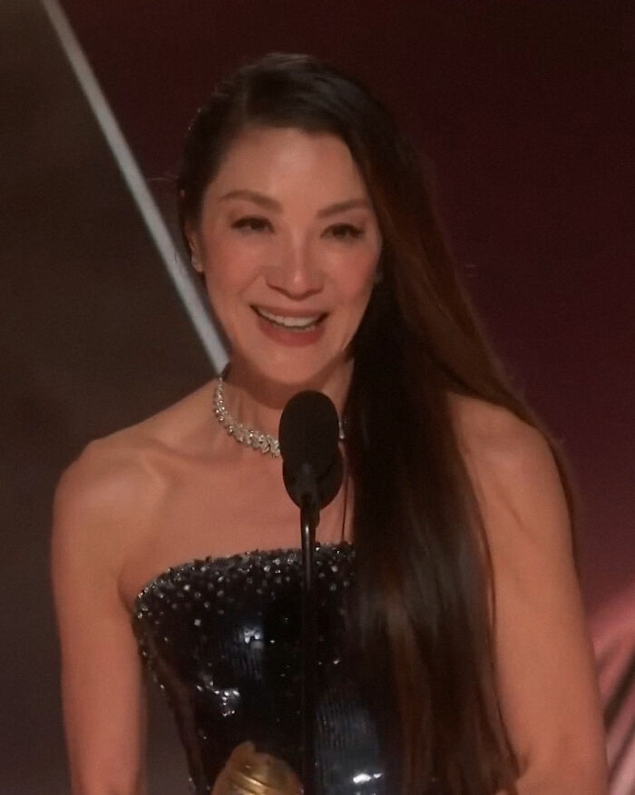 Michelle Yeoh at an event, wearing a strapless black dress and necklace, showing an extremely thin and worrying appearance. Michelle Yeoh at an event, wearing a strapless black dress and necklace, showing an extremely thin and worrying appearance.