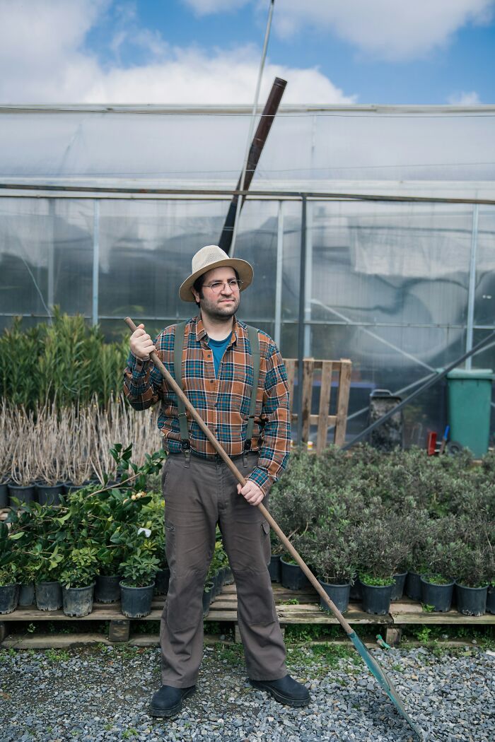 Man standing in a garden holding a long-handled tool, surrounded by plants, illustrating Karens so crazy scenarios.