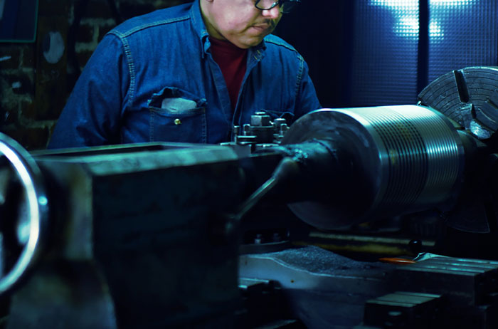 Man operating heavy machinery in a workshop, illustrating unexpected lives that ended in tragic ways.