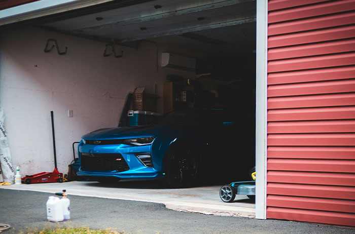 Blue sports car parked inside a partially open garage, illustrating unexpected stories of lives ending in surprising ways.