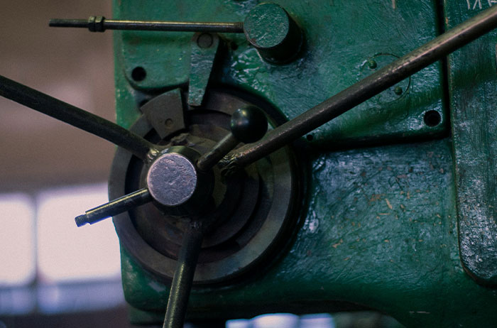 Close-up of an old green industrial machine with metal handles, related to stories of lives that ended unexpectedly.