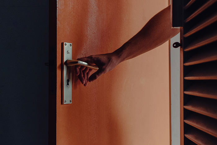Hand opening a door handle partially, symbolizing intuition and decision-making in an everyday setting.