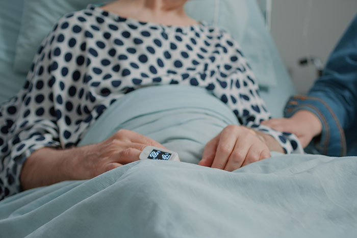 Woman in hospital bed with hand on pulse oximeter, illustrating women sharing times their intuition was spot on.