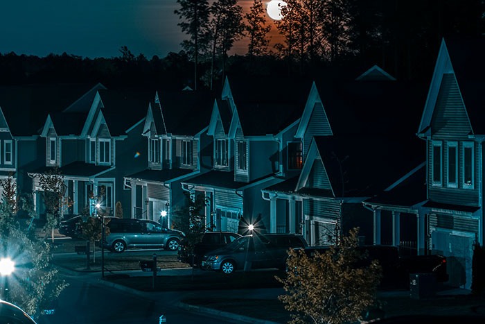 Nighttime view of suburban houses under moonlight, evoking a sense of calm and intuition in the quiet neighborhood.