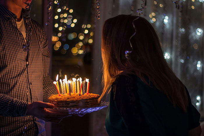 Woman celebrating a birthday with lit candles on cake held by a man, highlighting moments of intuition being spot on.