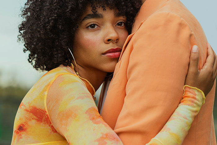 Woman with curly hair embracing a partner, showing trust and intuition in a close and emotional moment outdoors.