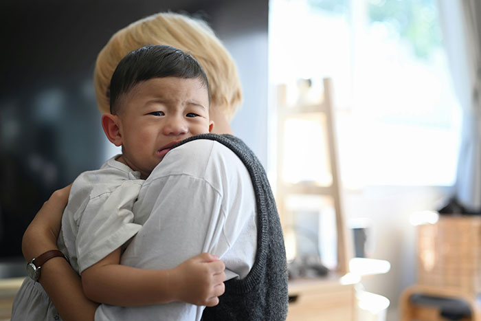 Woman comforting a crying child in a bright room, showing a moment of emotional intuition and care.