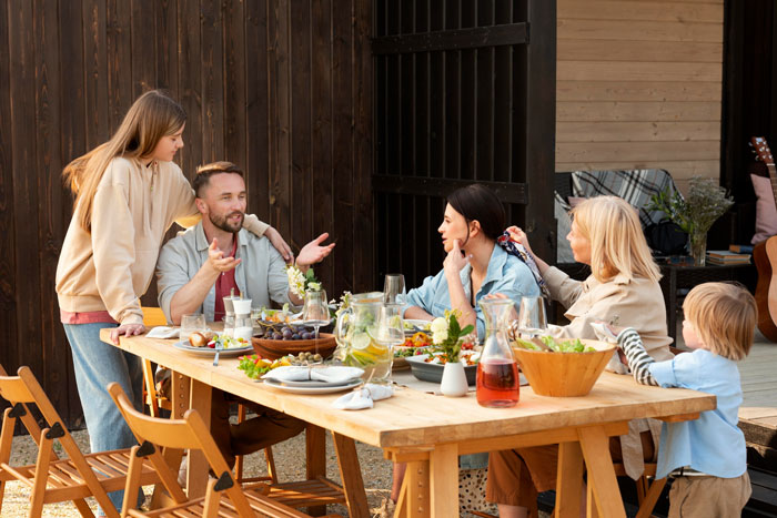 Family gathered at an outdoor meal with future MIL scheduling events conflicting with lady&rsquo;s work days causing tension.
