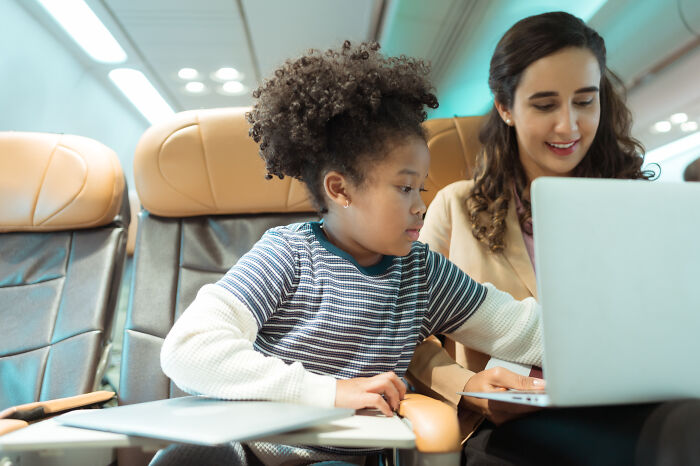 Flight crew and passenger in airplane cabin, sharing travel experiences during a flight horror story discussion.