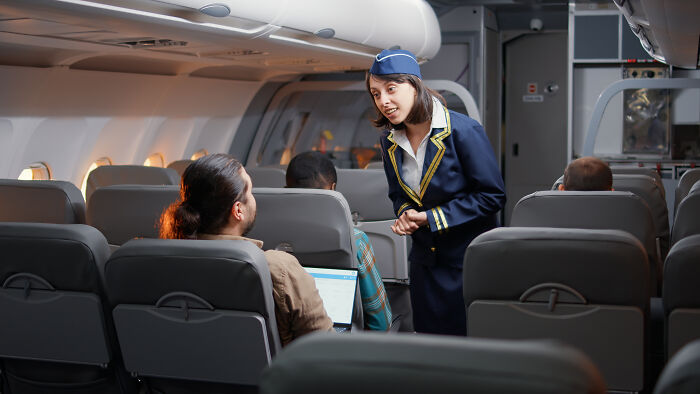 Flight crew member speaking to passengers during a tense flight sharing passenger horror stories onboard.
