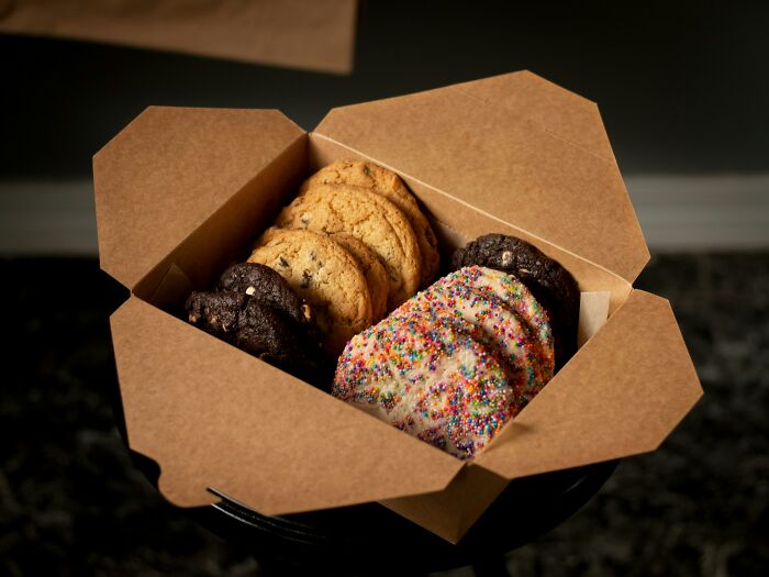Assorted cookies in a takeout box, symbolizing flight crew sharing passenger horror stories during worst hours of flights.