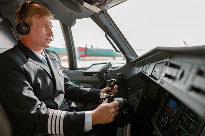 Pilot wearing uniform and headset operating cockpit controls during flight, illustrating flight crew passenger horror stories.