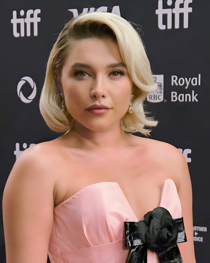 Florence Pugh at TIFF wearing a pink dress, sharing her experience with steamy scenes on film sets.