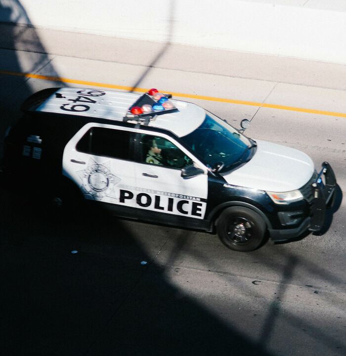 Police car parked on street during investigation of woman found chained in backyard in bizarre case.